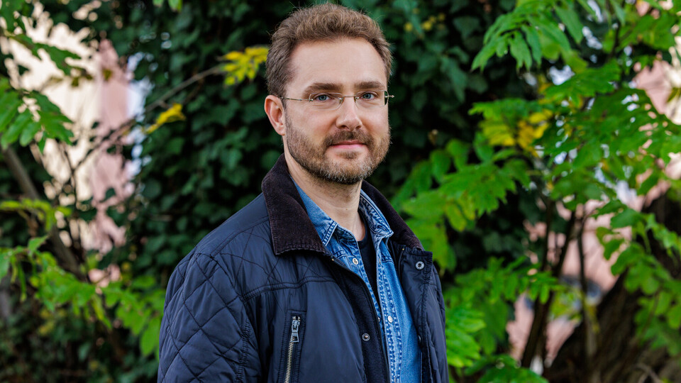 Prof. Dr. Ivan Balykin in blauer Jacke vor grünen Pflanzen.