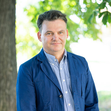  Prof. Henning Hillmann. Er schaut freundlich drein und trägt ein blaues Jacket über einem gestreiften Hemd.