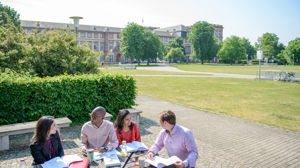 Vier Studierende lernen auf dem Außengelände der Universität Mannheim