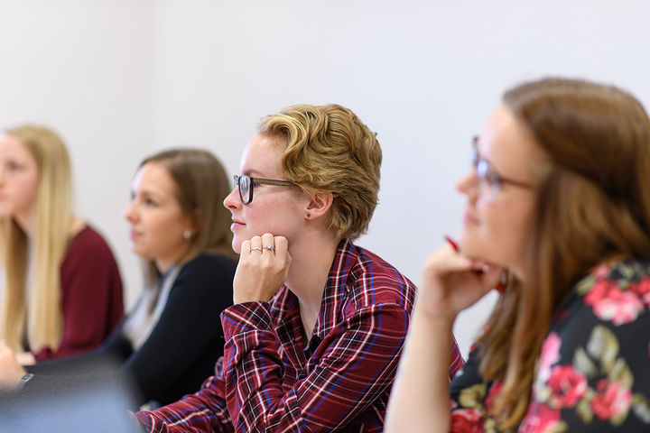 Studentinnen hören bei einem Vortrag zu.