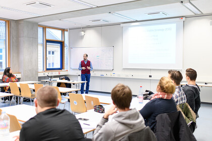 Dozent unterrichtet in einem Seminar, das Publikum hört ihm zu. 