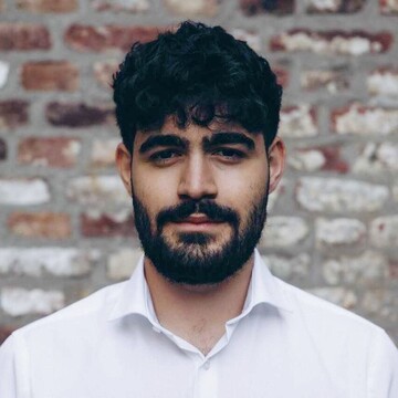 David Avagian. Er trägt ein weißes Hemd und steht vor einer Mauer.