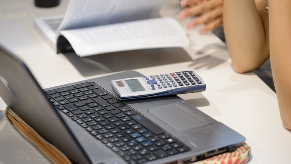 Laptop und Taschenrechner auf einem Tisch