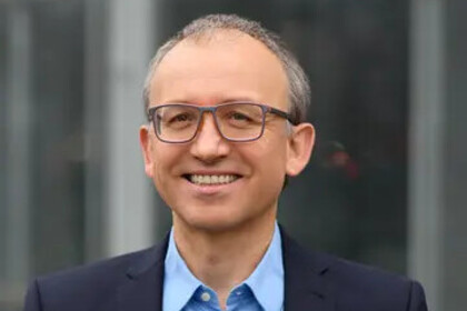 Thomas Gschwend trägt ein blaues Hemd und einen dunkelblauen Sakko und lächelt