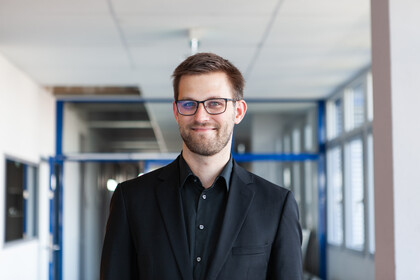 Porträt von Herrn Janke. Er trägt eine Brille und ein schwarzes Hemd.