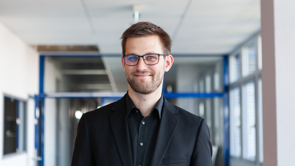 Porträt von Herrn Janke. Er trägt eine Brille und ein schwarzes Hemd.