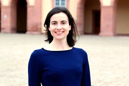 Teodora Vasilichi hat dunkle mittellange Haare und trägt ein blaues Oberteil. Sie lächelt in die Kamera.