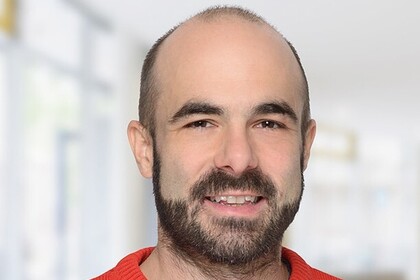 Portrait von Harald Fadinger. Er trägt einen roten Pullover und lächelt.
