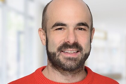 Portrait von Harald Fadinger. Er trägt einen roten Pullover und lächelt.