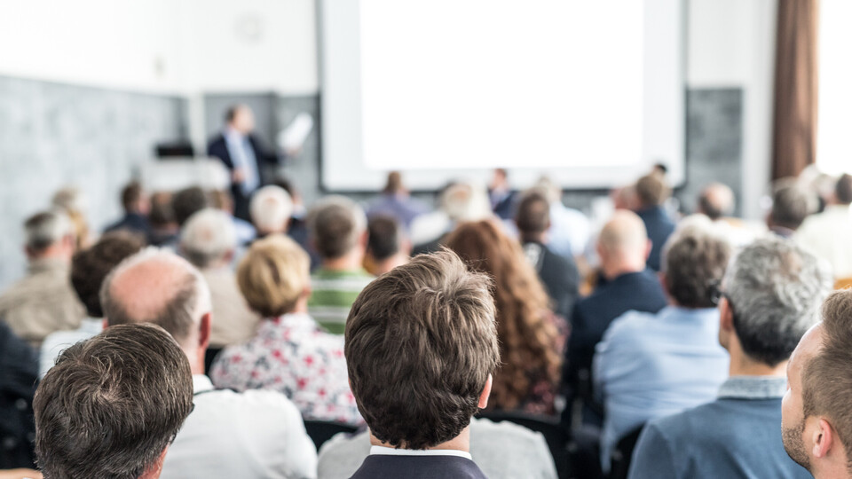 Redner hält einen Vortrag im Konferenzsaal bei einer geschäftlichen Veranstaltung. Publikum im Konferenzsaal. Konzept für Wirtschaft und Unternehmertum. Fokus auf unerkennbare Menschen im Publikum