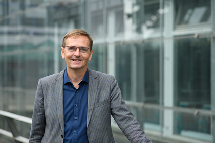 Oliver Dickhäuser trägt ein blaues Hemd und ein graues Sakko.