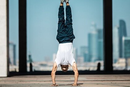 Eine Person mit weißem T-Shirt und dunkler Hose macht einen Handstand. Unten rechts ist das Logo des IFS- Institut für Sport der Universität Mannheim.