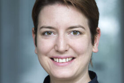 Katja Möhring hat kurze braune Haare. Sie trägt eine dunkelblaue Bluse und lächelt in die Kamera