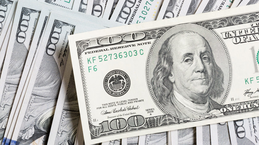 100-Dollar-Schein, im Hintergrund liegen weitere Dollar-Scheine.