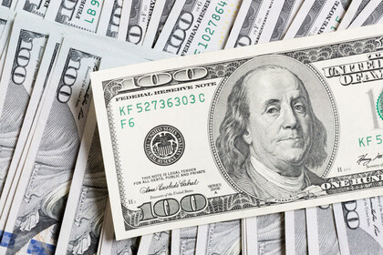 100-Dollar-Schein, im Hintergrund liegen weitere Dollar-Scheine.