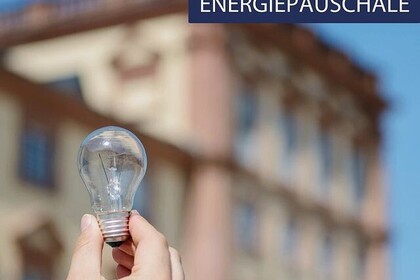 Eine Hand hält eine Glühbirne in die Luft. Im Hintergrund das Schloss Mannheim. Darauf der Text: Neue Infos zur Energiepauschale. Link: Instagram-Post Energiepauschale für Studierende