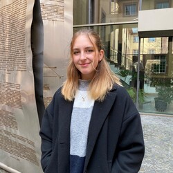 Leia Braunagel hat blonde Haare. Sie trägt einen schwarzen Mantel und einen Wollpullover.