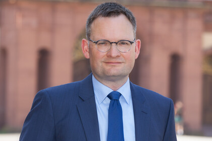 Portrait von Philipp Gassert. Er trägt einen blaugrauen Anzug mit blauer Krawatte. 