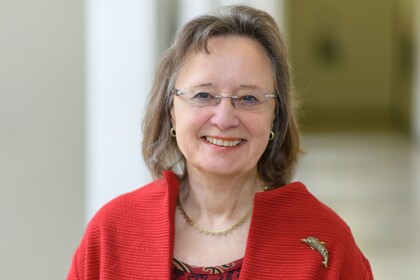 Prof. Rosemary Tracy trägt ein rotes Jacket mit Delfinbrosche.