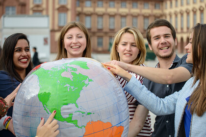 Studierende halten gemeinsam einen großen Globus