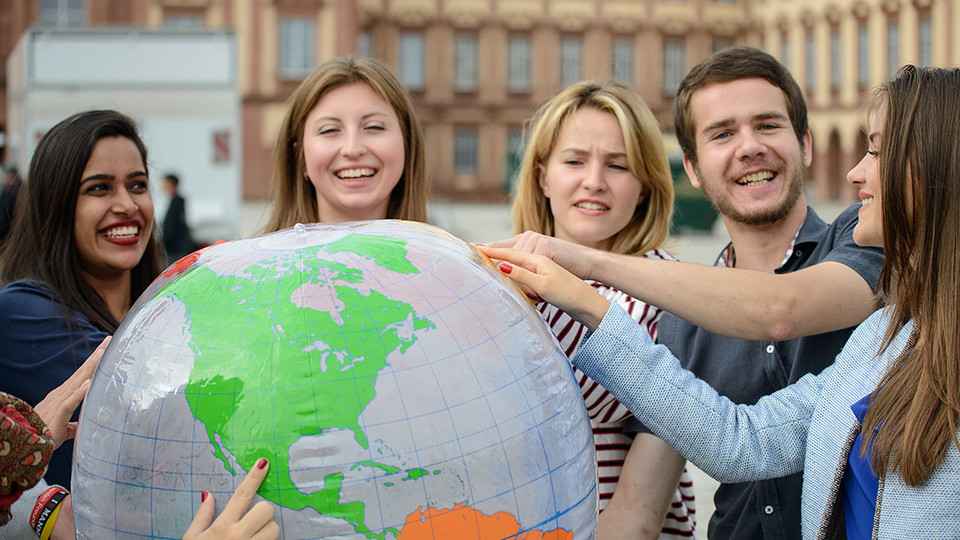 Studierende halten gemeinsam einen großen Globus