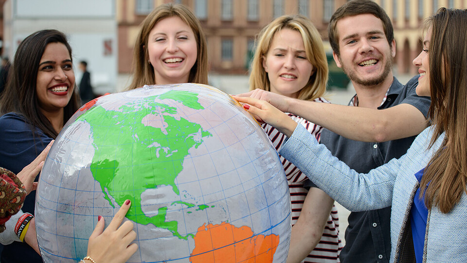 Studierende halten gemeinsam einen großen Globus