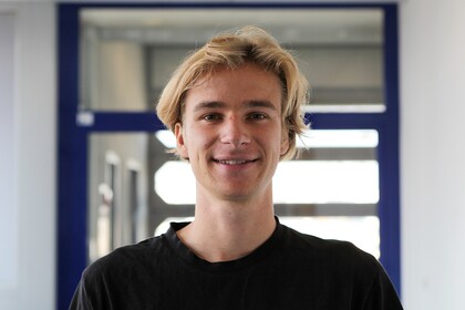 Oliver Rittmann with black T-shirt in front of glass door