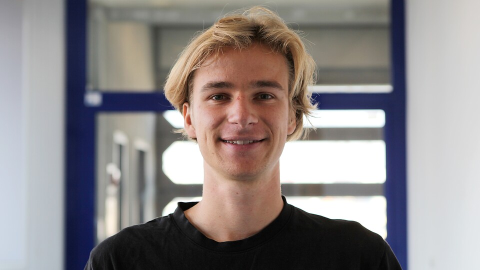Oliver Rittmann with black T-shirt in front of glass door