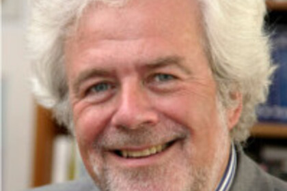 Portrait eines Mannes. Er schaut lächelnd in die Kamera. 