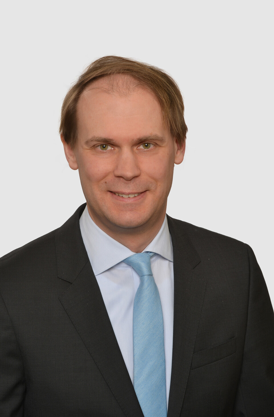 Prof. Bischof hat kurze Haare und trägt ein dunkles Jacket, ein helles Hemd und eine türkisfarbene Krawatte.