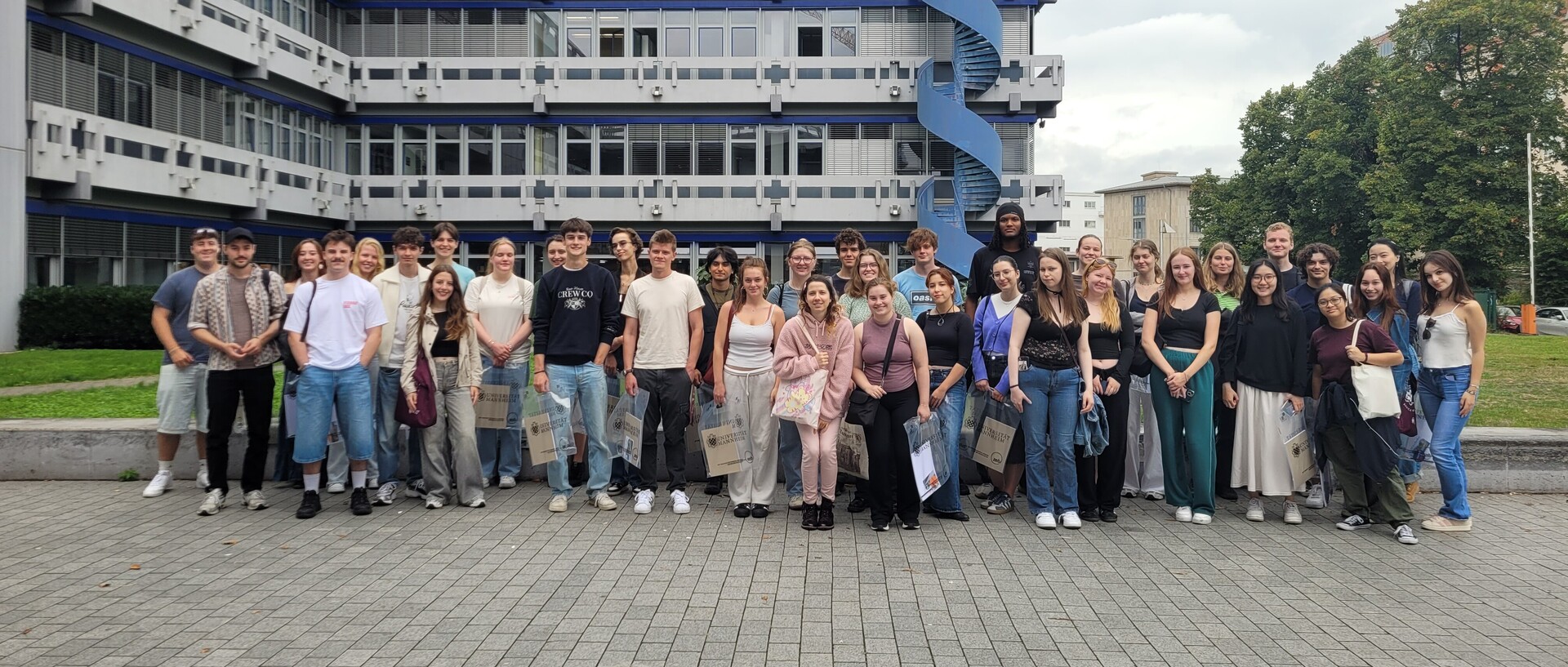 Gruppe an Studierenden steht vor einem Gebäude. 