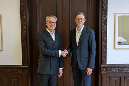Dekan Joachim Lutz und prof. Dr. Jens Förderer stehen vor einer verzierten Holztür und geben sich die Hand
