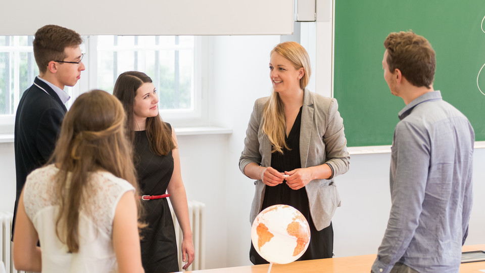 Personengruppe steht um Globus herum