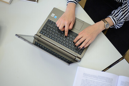 Zwei Hände tippen auf einem Laptop.