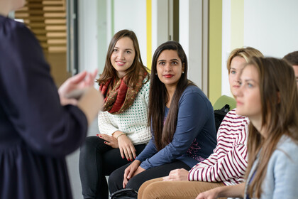 Mehrere Frauen hören einer sprechenden Person aufmerksam zu.