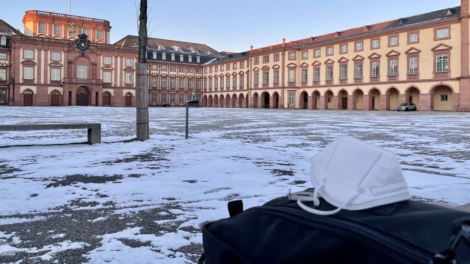 Maske auf Rucksack vor verschneitem Ehrenhof