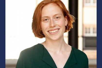 Theresa Poralla hat kurze rötliche Haare. Sie trägt ein dunkelgrünes Oberteil und blickt lächlend in die Kamera. Unten steht "Hashtag 10 Jahre Deutschlandstipendium".