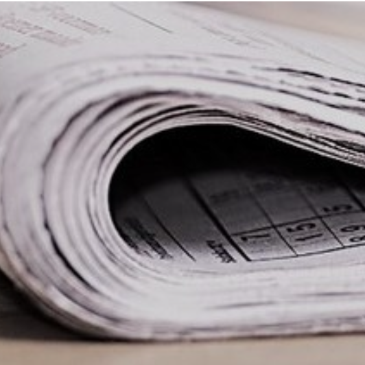 Eine Zeitung ist halb gefallen und liegt auf einer Oberfläche.