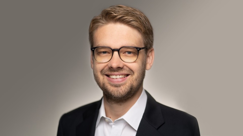 Portrait von Marc Lerchenmüller. Er trägt ein weißes Hemd sowie einen schwarzen Blazer und lächelt.