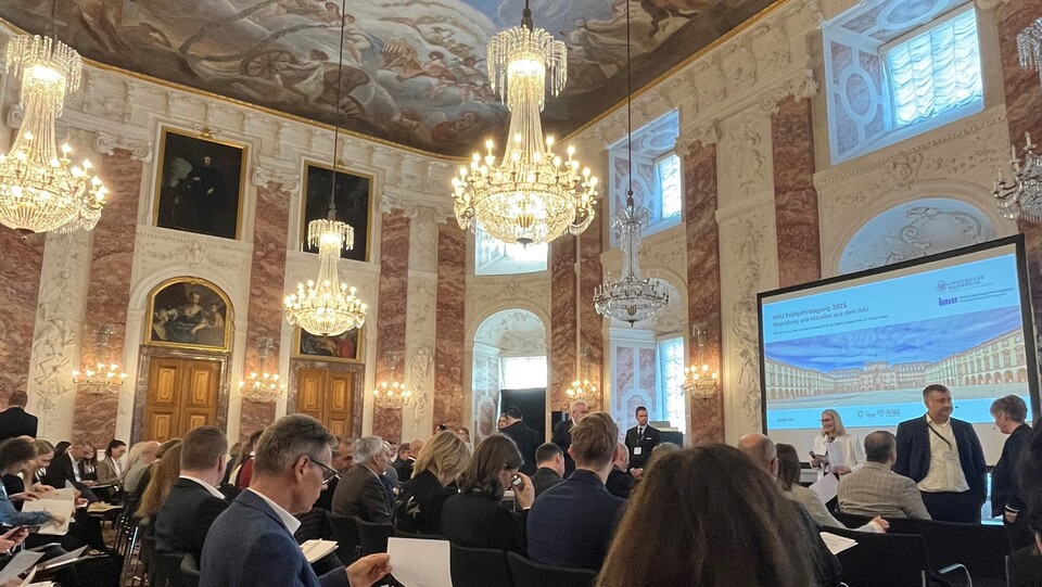 Rittersaal mit prunkvoller Decke und den Referent:innen am Pult
