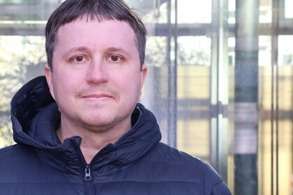 Ein Portrait von Prof. Eger: Ein Mann in Jacke steht vor der Glasfront der WIM