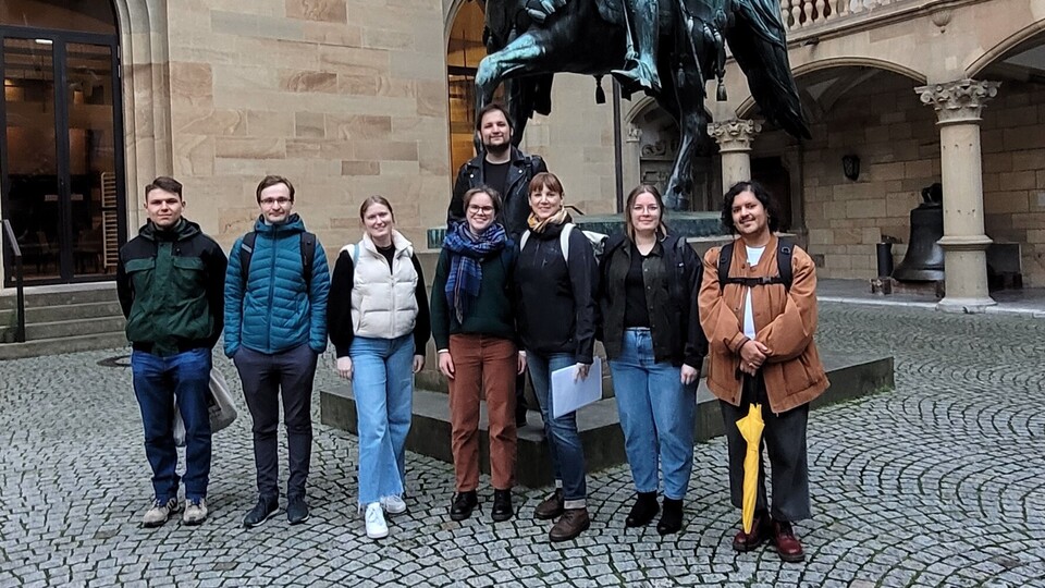 8 Personen vor einer Statue im Innenhof eines Schlosses