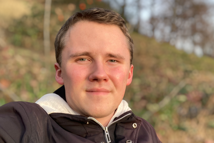 Andreas Hamann in einer braunen Jacke im Wald.