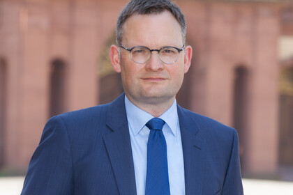 Portrait von Philipp Gasssert. Er steht in einem blauen Anzug vor dem Mannheimer Schloss.