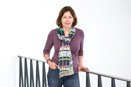 Michaela Wänke steht an einem Geländer und trägt ein lila farbiges Oberteil, einen bunten Schal sowie eine blaue Jeans.