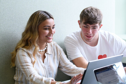 Eine Studentin und ein Student sitzen vor einem Tablet.