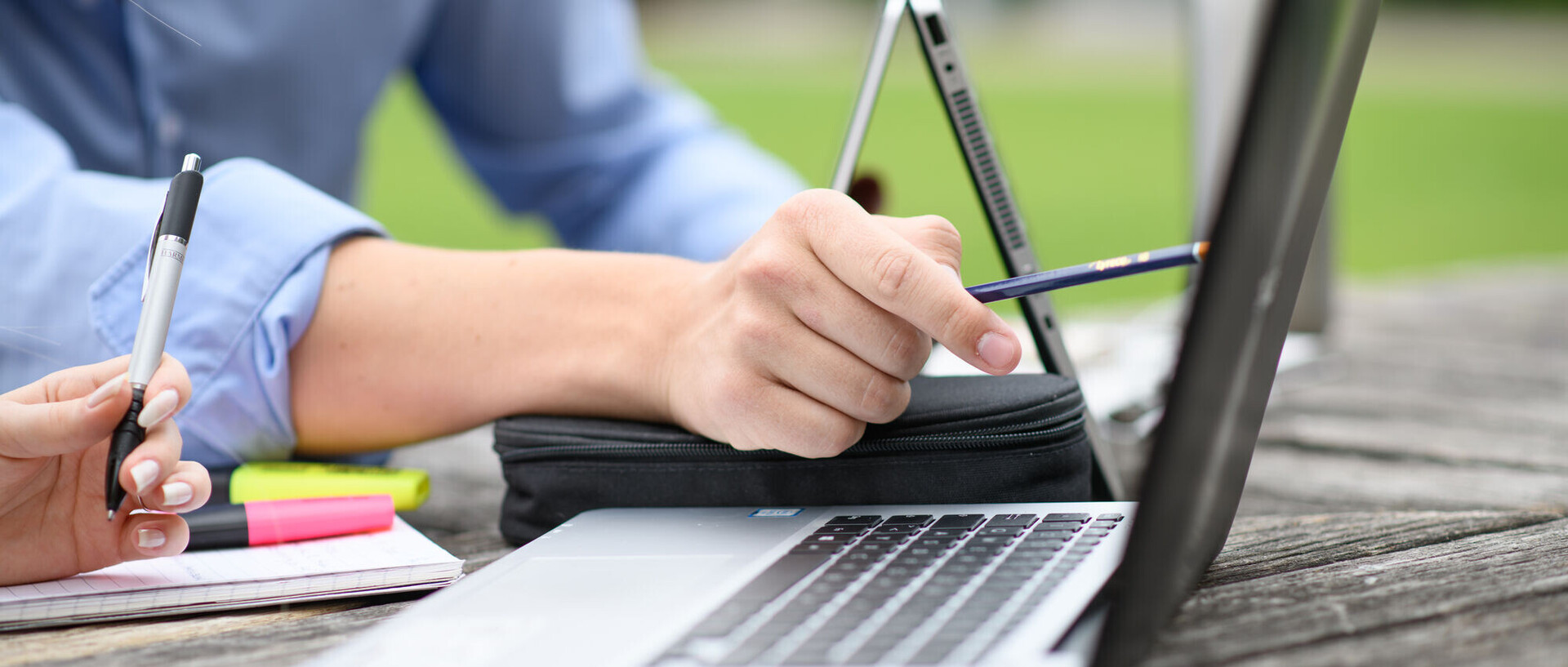 Two people studying outside with their computers.