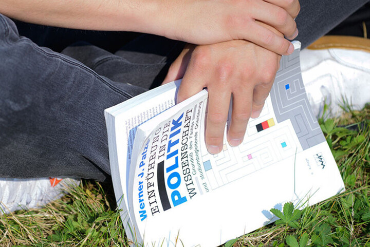 Bild zeigt sitzende Person mit Buch in Händen