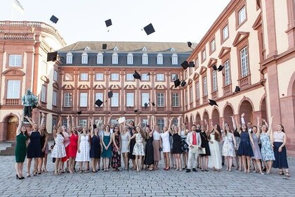 Aufnahme von Absolventen und Absolventinnen, die ihre Absolventenhüte in die Luft werden neben dem Westflügel der Universitä Mannheim