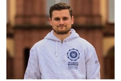 Porträt des Studenten David Schmidt in der Reihe "testimonialtuesday". Er hat braune kurze Haare und einen Bart und trägt eine graue Kapuzenjacke der Uni Mannheim. Link: Instagram Post testimonialtuesday